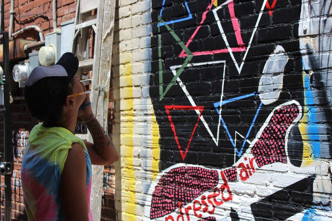Dani Greene visualizes where to put the finishing touches on the mural of Richard Hell outside of J. Gumbo’s restaurant in Lexington, Ky. on June 21, 2019. Greene and Kiptoo Tarus are freelance artists who were hired to help the Montessori students paint the mural of Hell.