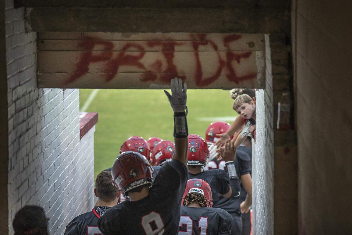 Mayfield’s Jax Rogers reaches up to touch the word, “Pride,” painted in the tunnel leading from the Cardinals’ locker room to the field.