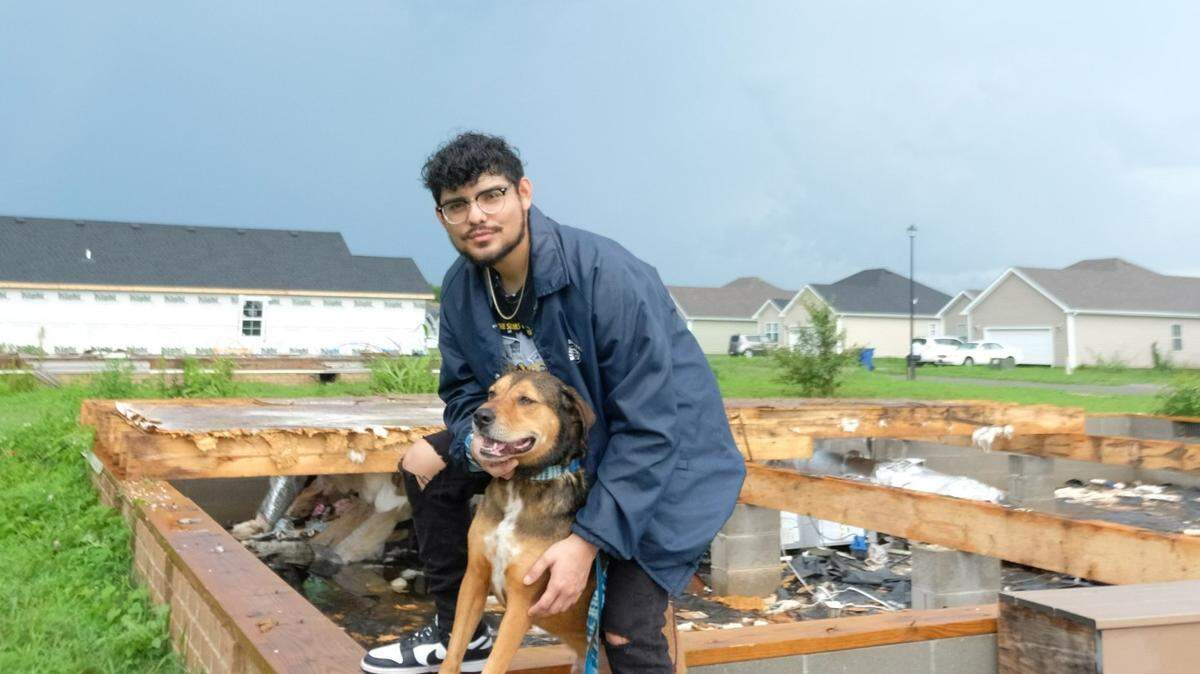 Francisco Serrano, of Bowling Green poses with his dog, Simba, in the ruins of his parents' home. His parents’ home was destroyed by a tornado that ripped through the Moss Creek neighborhood in December of 2021. 