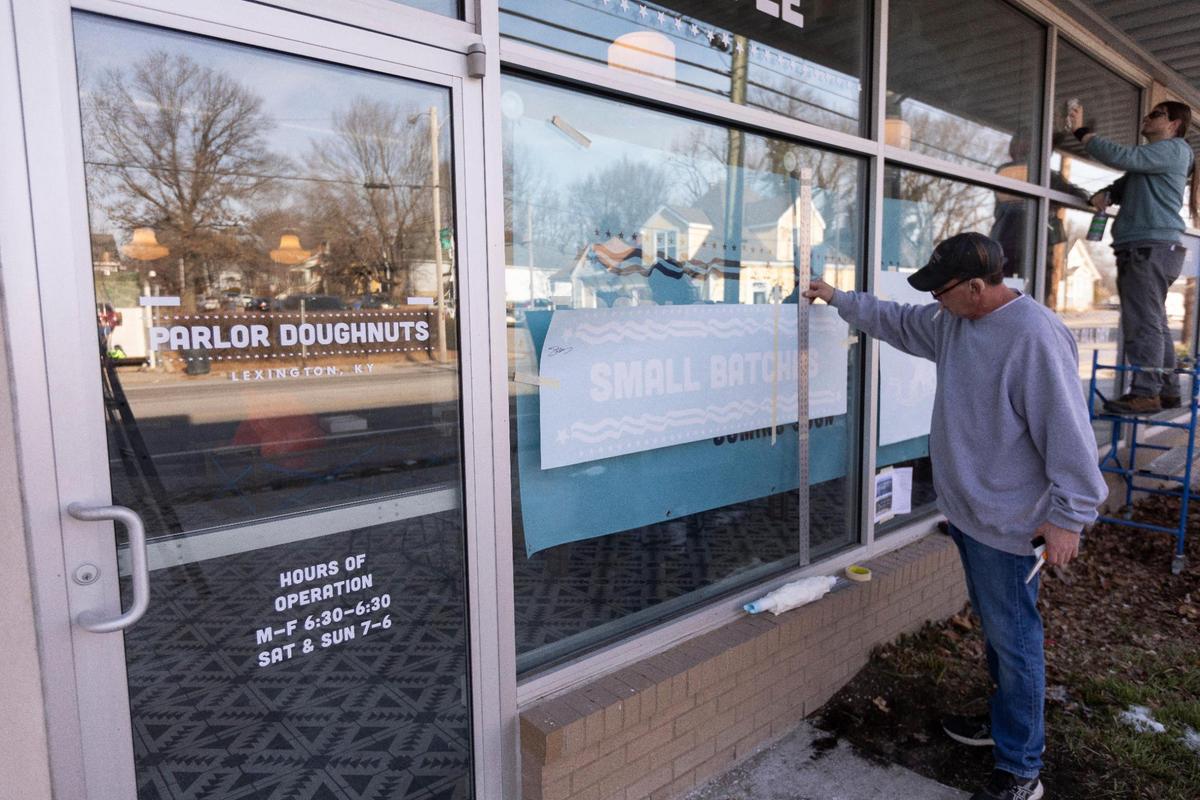 Workers install signs at the Parlor Doughnuts Lexington location Tuesday on Euclide Avenue that hopes to have its soft opening this weekend serving flaky, croissant-style “cronuts.”