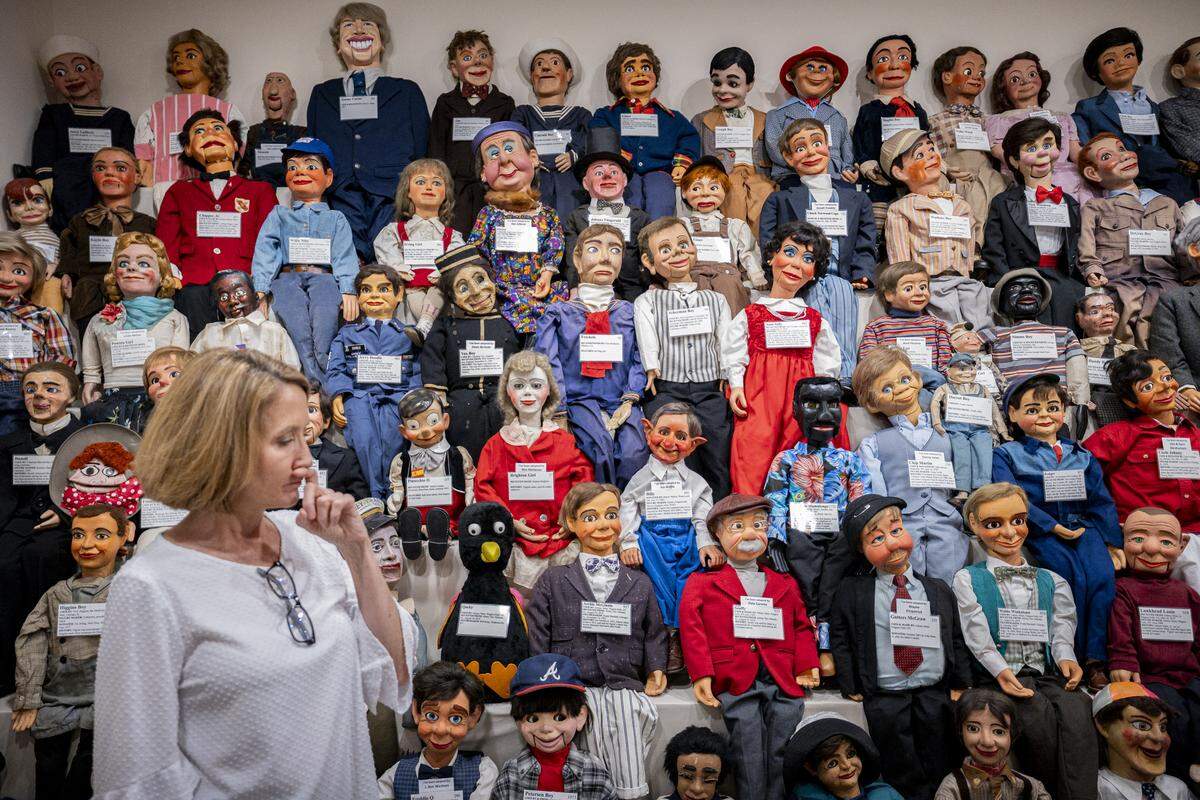 Lisa Sweasy stands next to a wall of ventriloquial figures during a tour on Tuesday, Aug. 12, 2025, at Vent Haven Museum in Fort Mitchell, Ky.