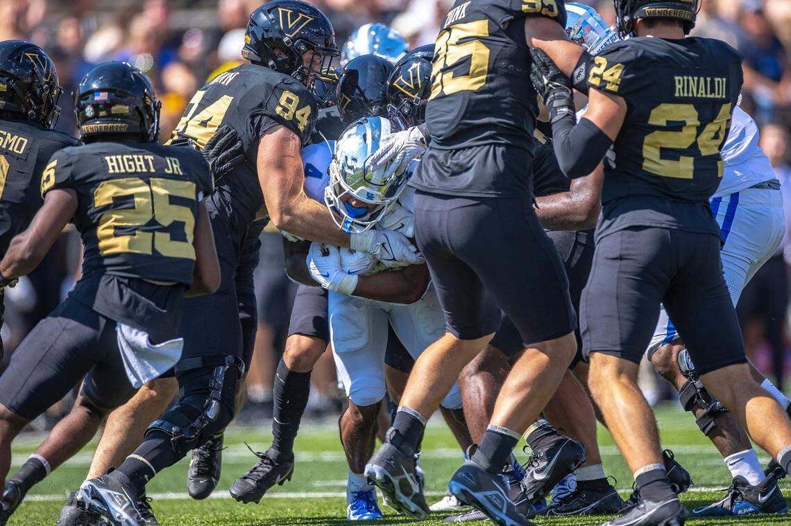 Kentucky running back JuTahn McClain, center, tries to run through a line of Vanderbilt defenders, including defensive lineman Bradley Mann (94).