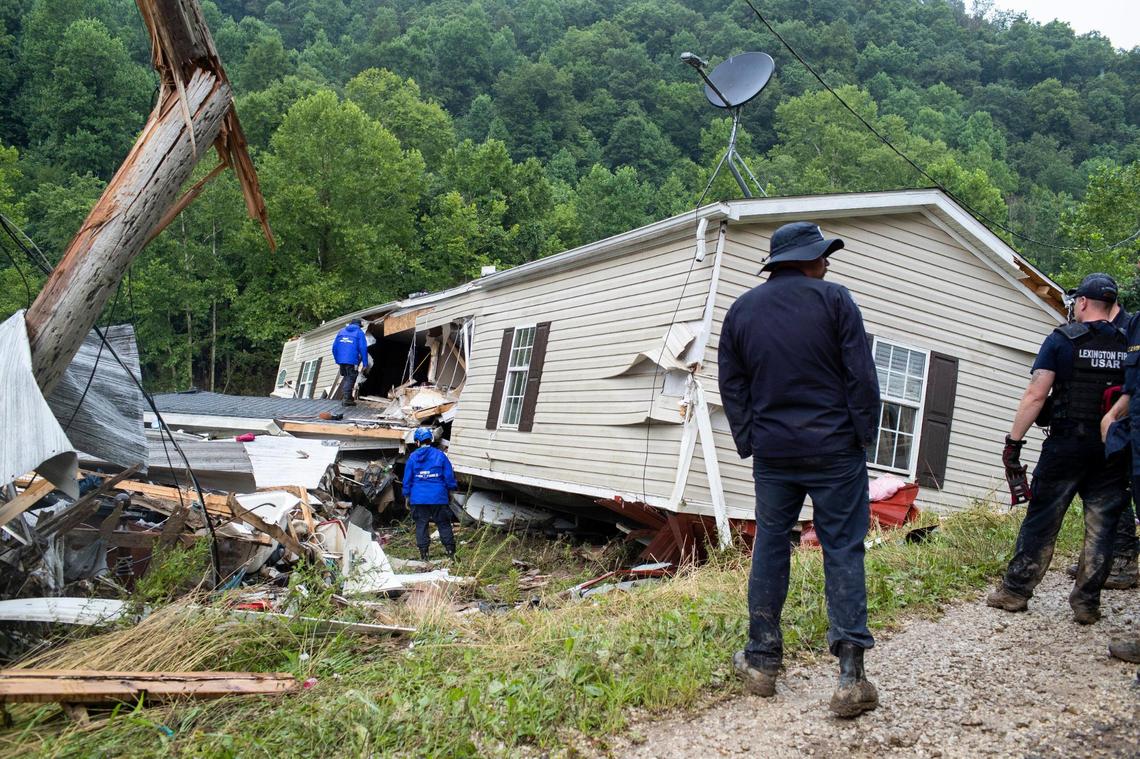 Members of the Lexington Fire Department look through the wreckage of a home while operating as search and rescue units along KY-476 along Troublesome Creek in Breathitt County, Ky., Sunday, July 31, 2022.