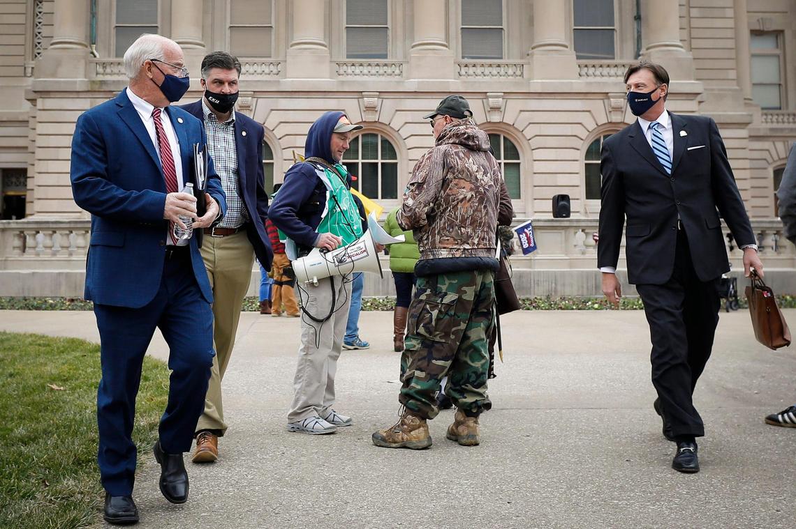 Senators Dennis Parrett, D-Elizabethtown, from left, Jared Carpenter, R-Berea, and Brandon Smith, R-Hazard, right, walk past demonstrators a protest at the State Capitol in Frankfort, Ky., Saturday, Jan. 9, 2021.
