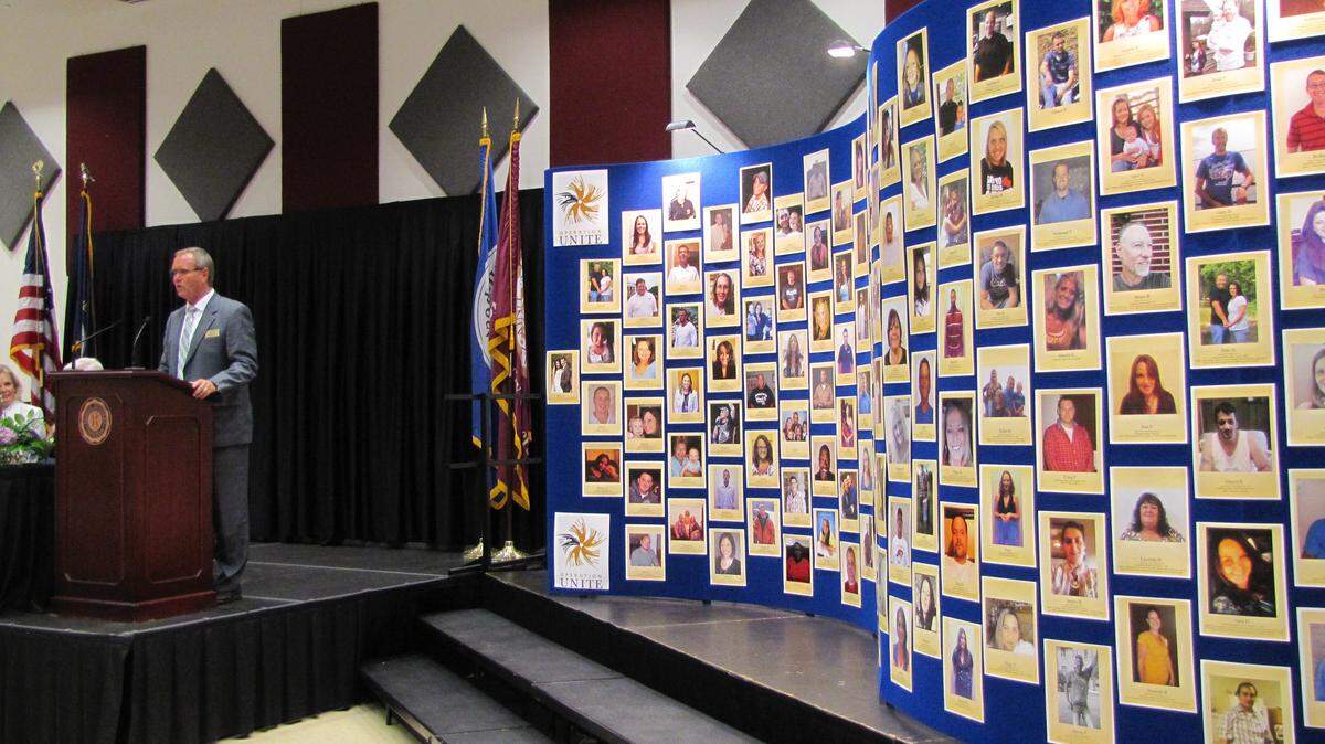 Dan Smoot, president of Operation UNITE, spoke Aug. 16 at an event in Manchester celebrating stories of people who had beaten drug addiction. At right is Operation UNITE’s Wall of Hope, featuring people who had overcome their dependence on drugs. Photo by Bill Estep | Staff