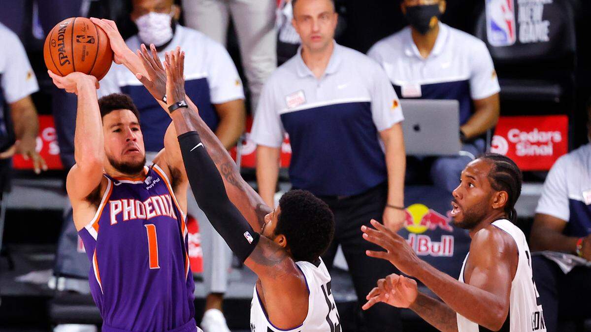 The Suns’ Devin Booker shot the game-winning basket over the Clippers’ Paul George (13) on Tuesday in Lake Buena Vista, Fla.