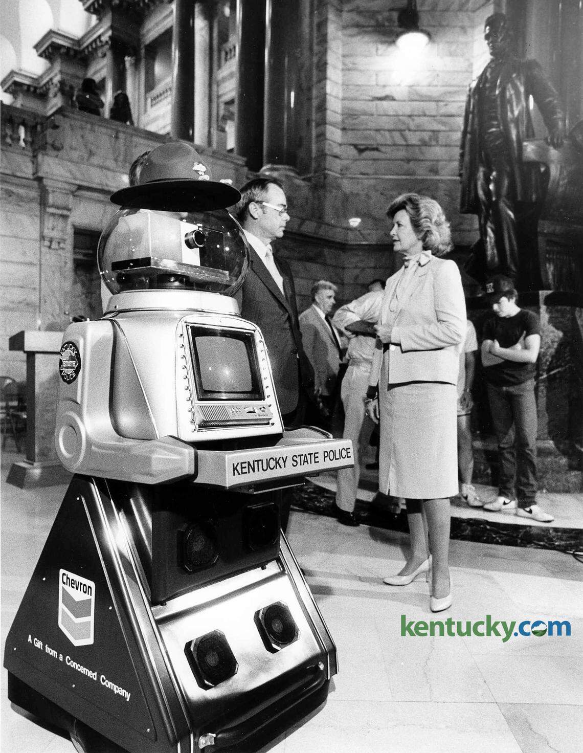 A robot was sworn in as a Kentucky State Trooper Aug. 6, 1984 at the state capital in Frankfort. The robot, which was donated by the Chevron Corp. at a cost of $14,750, was used to teach traffic safety in Kentucky schools. The robot was sworn in by Kentucky Chief Justice Robert F. Stephens and given badge No. 219. In the background, Kentucky State Police Commissioner Morgan T. Elkins and Gov. Martha Layne Collins talk in the Capitol rotunda. The governor tried to be kind during ceremony. “I’m saying he, but we’ll let that go,” she said. Stephens was even a bit more serious that the occasion may have demanded when he called for the officer candidate to repeat the oath of office. Following Stephens’ lead, the robot promised to “promote the peace and safety of this commonwealth, to serve mankind by responding to the needs of you humanoids... to the best of my ability, batteries and computer willing.” Chevron provided a $500 savings bond that will go to the winner of a contest to name the newest trooper. 