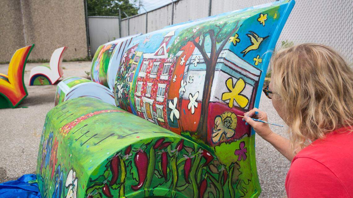 Anne Allen touches up the bench she worked on with students from the Sayre Middle School at the old bus depot on Tuesday. The bench is a depiction of "All Rise: A History of Sayre School" by William T. Williams. The benches are going to be previewed on Friday in Gratz Park and then dispersed around Lexington for display into November.