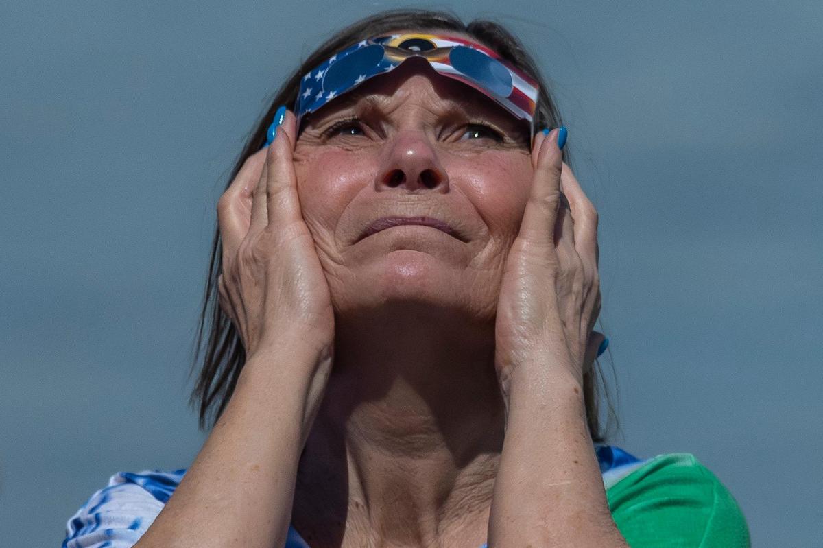 A woman looks on during totality of a solar eclipse from the riverfront in Paducah, Ky., on Monday, April 8, 2024.