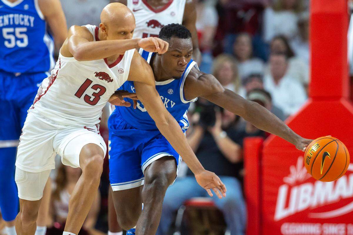 Kentucky’s Oscar Tshiebwe (34) and Arkansas’ Jordan Walsh (13) reach for the ball during Saturday’s game at Bud Walton Arena in Fayetteville, Ark.