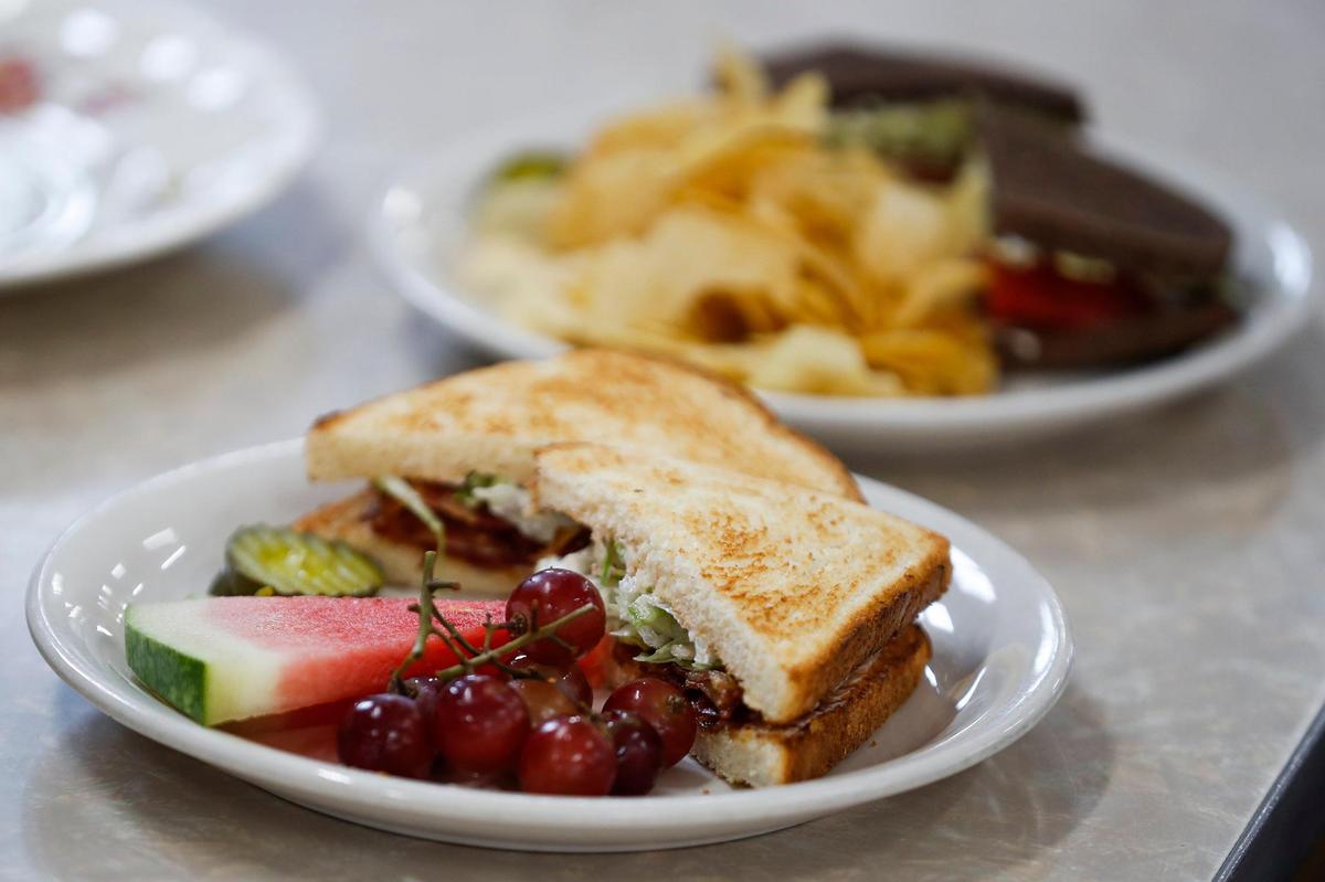 A BLT served with pickles, grapes and watermelon sits near a Paris BLT, which comes with avocado and served with chips at Lil’s Coffee House.