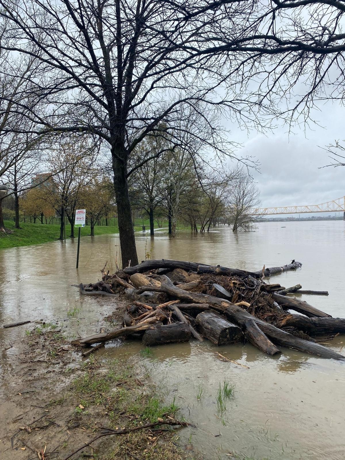 A swollen Ohio River spills onto a pedestrian walkway in Louisville Saturday afternoon, leaving debris in its path. The river has already reached flood stage and is expected to reach top-10 record levels in city history.