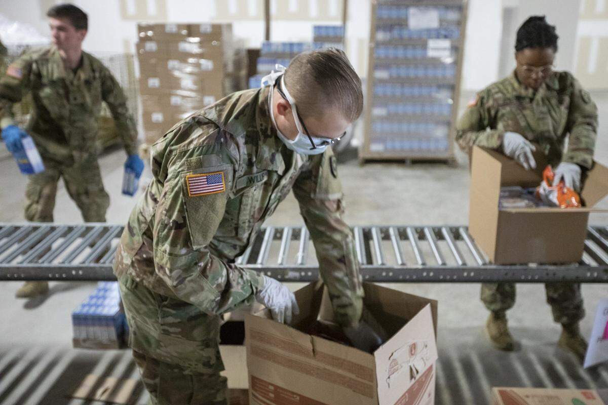 Eddie Willis, center, of the Kentucky National Guard, helps prepare boxes of food Tuesday for Lexington’s God’s Pantry Food Bank.