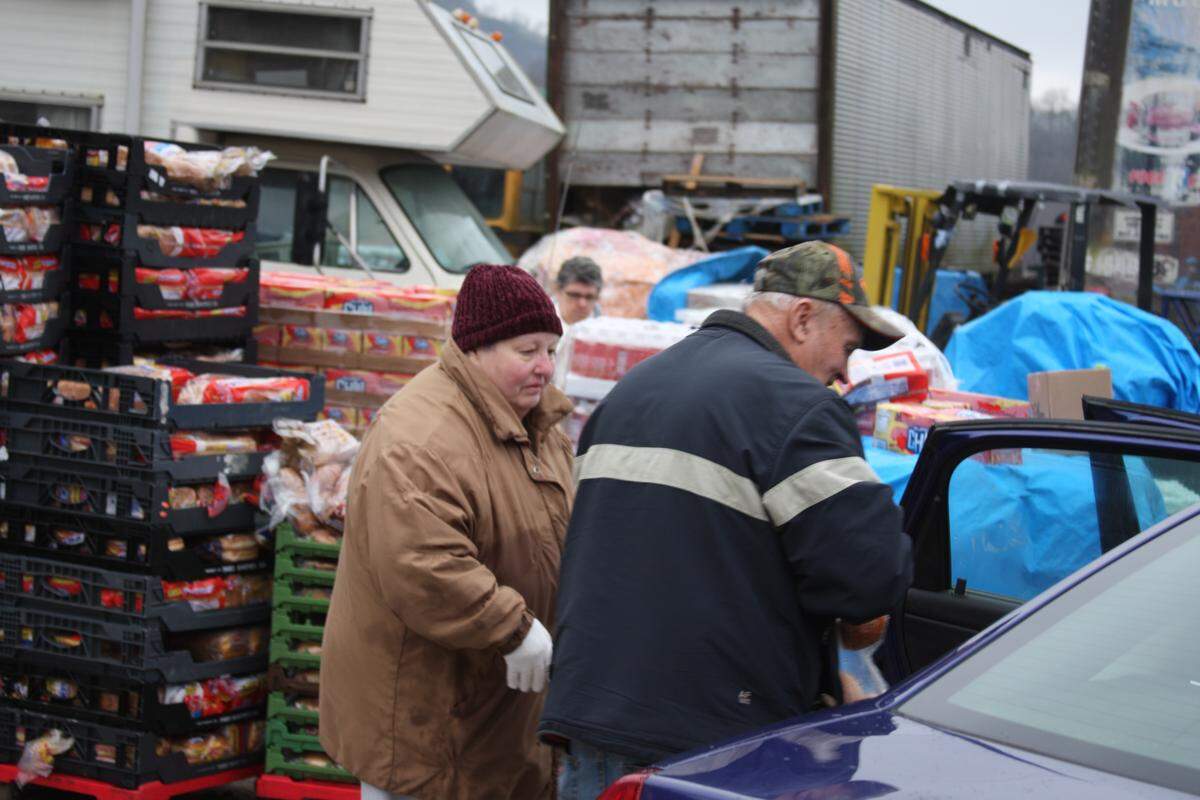 Thankful Heart Food Pantry volunteer Glenda Rogers helps distribute loaves of bread to pantry recipients on Friday.