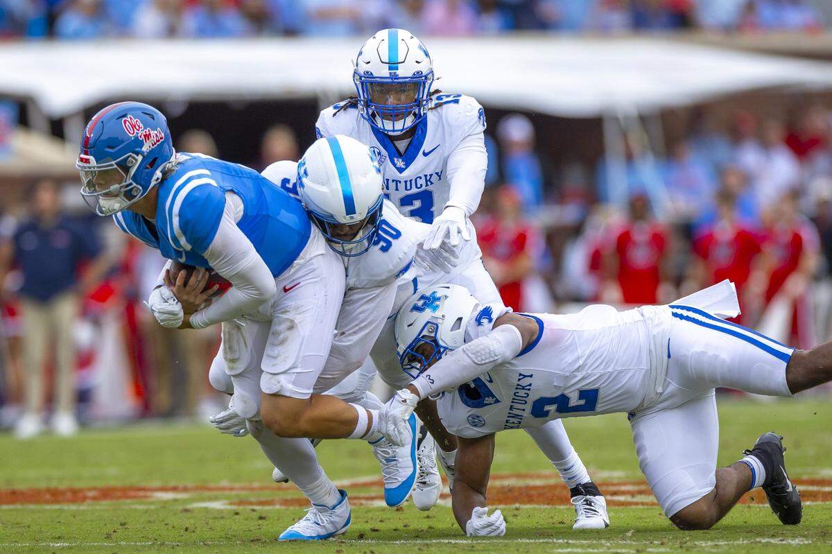 Kentucky defenders Tre’vonn Rybka (90), J.J. Weaver (13) and Jamon Dumas-Johnson (2) chase Ole Miss quarterback Jaxson Dart during the Wildcats’ win in Oxford, Mississippi.