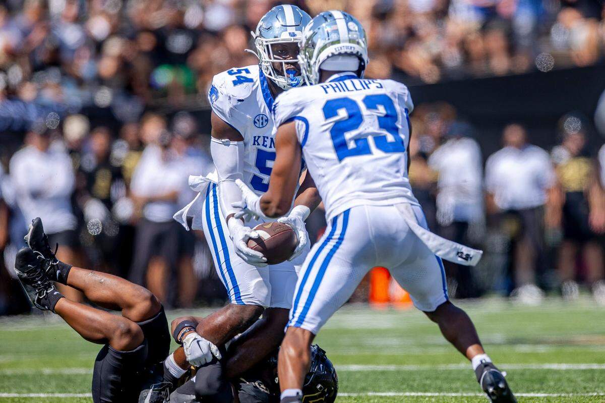 After intercepting the ball, Kentucky linebacker D’Eryk Jackson (54) pitches the ball to defensive back Andru Phillips (23), who ran it back for a large gain against Vanderbilt at FirstBank Stadium in Nashville on Saturday.