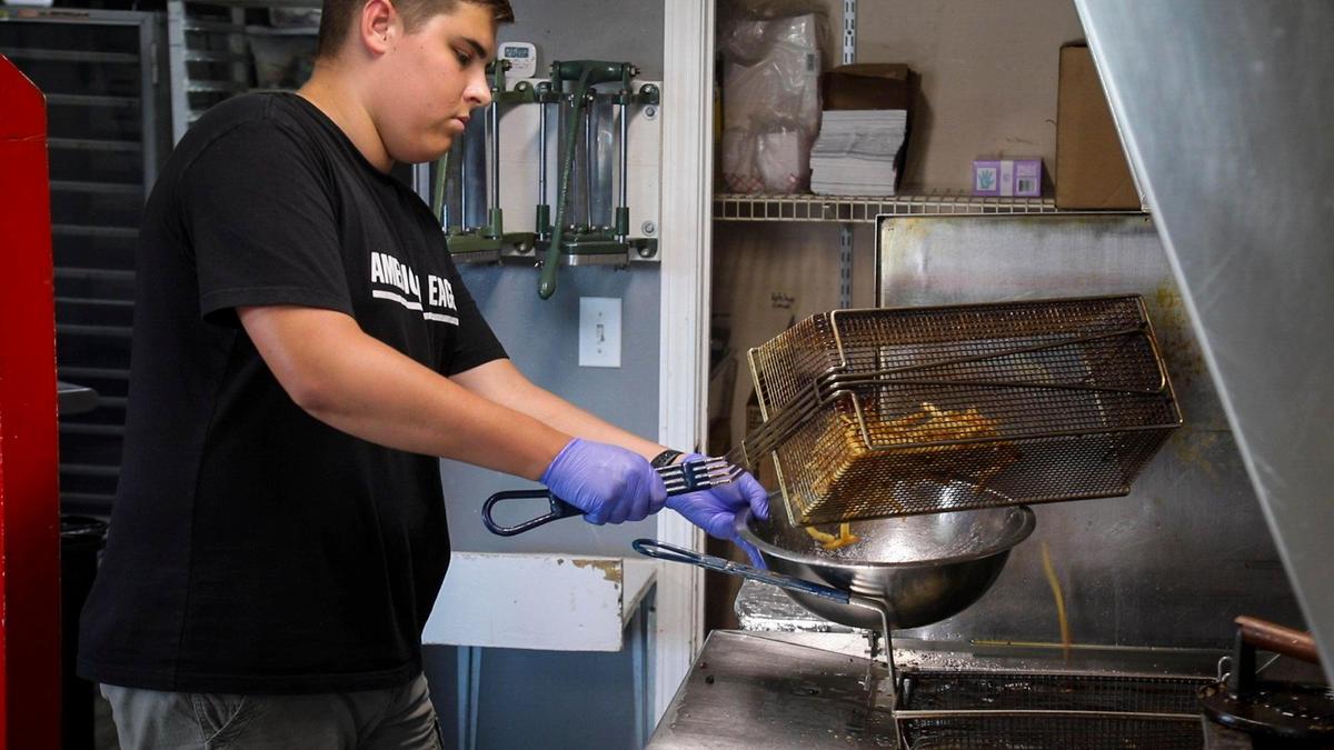 Brayden Sturgill prepares twice-fried fries made with local potatoes July 10 at the Drive-In restaurant in Olive Hill. Bacon and ranch can also be added to fries.