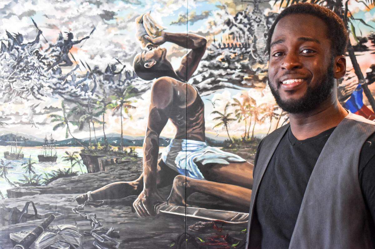 David Laurenvil built his American fusion cuisine on the traditional Haitian Creole cooking of his mother, Fida Noel. The painting behind him is local artist Agustin Zarate’s “The Black Maroon,” celebrating Haiti’s struggle for independence from France in 1804.