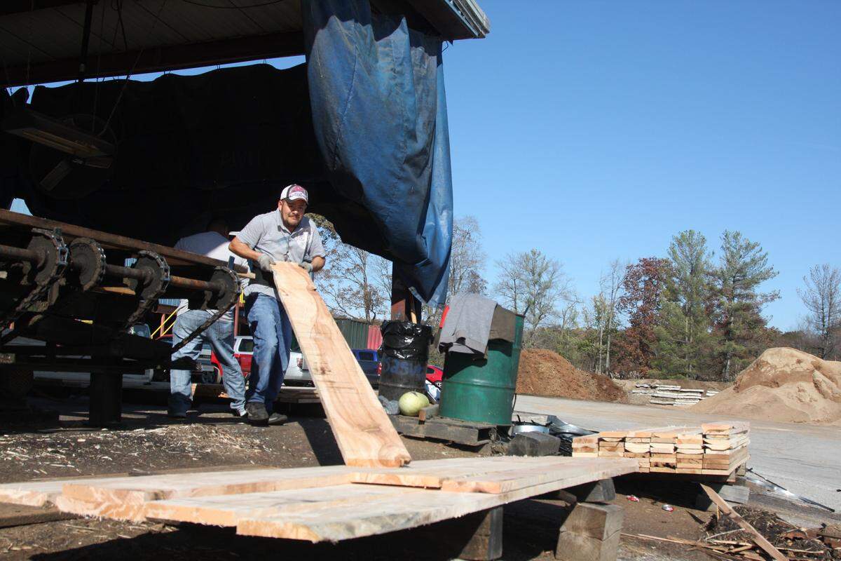 Jose Rosas, an employee of Harold White Lumber, Inc., stacks wood at the company’s lumber yard near Morehead.