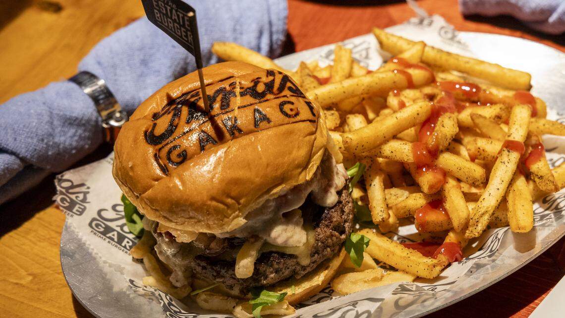 The Estate Burger with Ford’s Fries at Ford’s Garage features smoked Gouda cheese, sweet red onion marmalade, arugula, tomato, fried onion straws and white truffle bacon aioli for $16.99, photographed Tuesday, Nov. 4, 2025 in Lexington, Ky. Each of the 12 burgers on the menu are topped with artisan buns branded with the Ford’s Garage logo. 