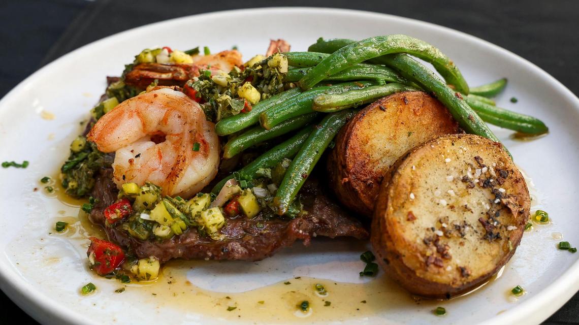 The Surf & Turf dish ($42) at Azur Restaurant and Patio, shown Monday, May 20, 2025 in Lexington, Ky. Marinated and then grilled skirt steak is topped with a mint and pineapple chimichirri and shrimp and then served with sautéed haricots verts and melting potatoes.
