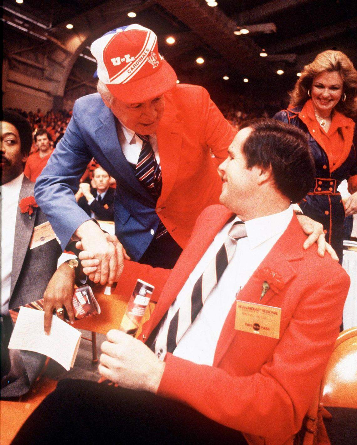 Kentucky Governor John Y. Brown Jr., wearing a blue and red sports coat and cap representing both the University of Kentucky and the University of Louisville greeted UL coach Denny Crum prior to the NCAA Mideast Regional final in Knoxville, TN, March 26, 1983. UL won the first “Dream Game” between the two state schools 80-68. At right rear is Gov. Brown’s wife, Phyllis George Brown. The Wildcats take on the Cardinals in Rupp Arena today 1pm. Photo by Charles Bertram | Staff