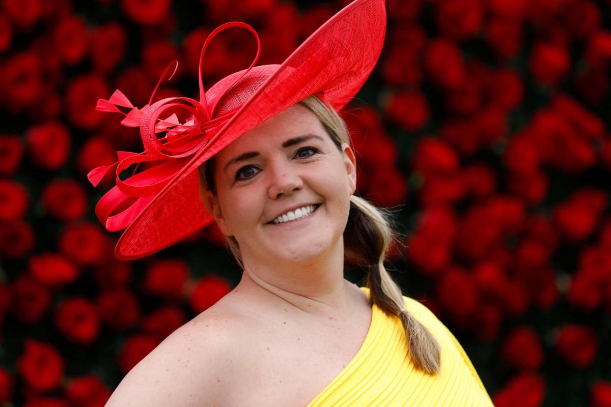 Rebecca Holwerda, from Indianapolis, wears a red had and fascinator with a yellow off the shoulder, ankle-length at Churchill Downs in Louisville, Ky., Saturday, May 7, 2022. “Yellow makes me happy,” she said.