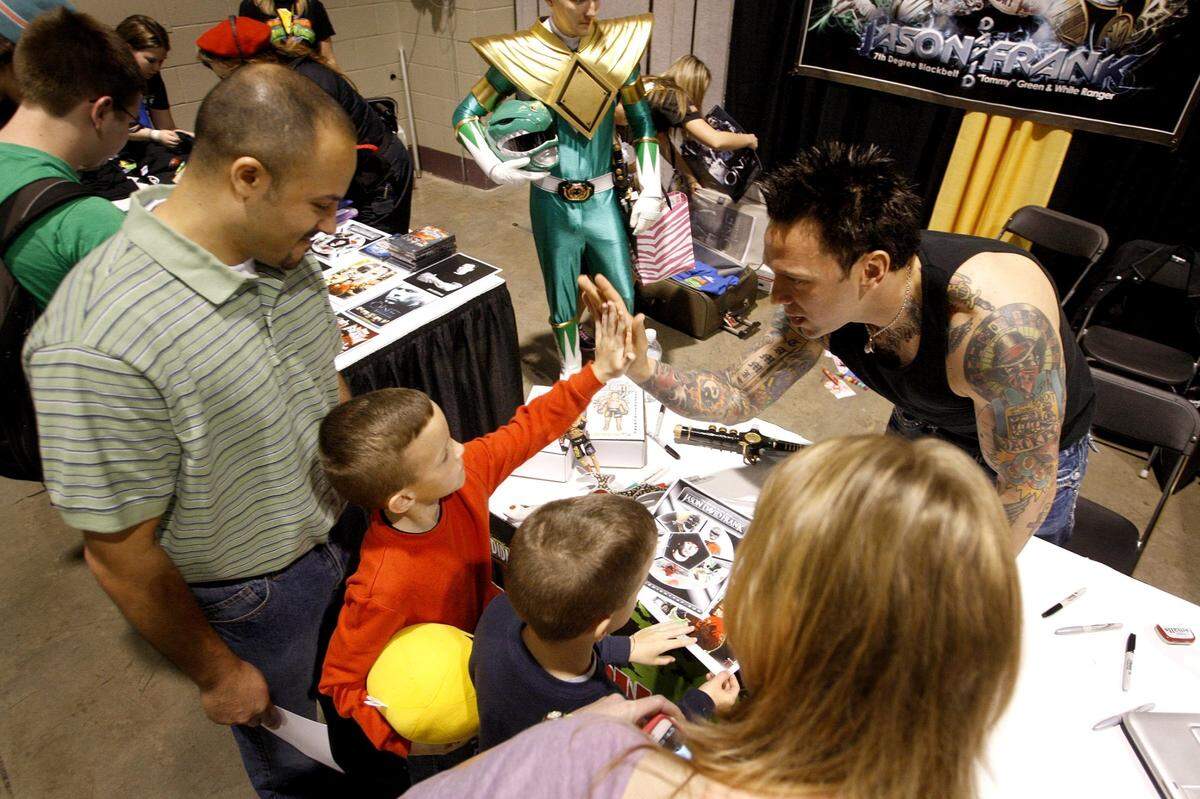 Christian Elzokari, 8, high fives Jason David Frank, right, as Elzokari’s father, Mike, at left, brother Mason and mother Heather Elzokari look on during the the first Lexington Comic and Toy Convention in 2012.