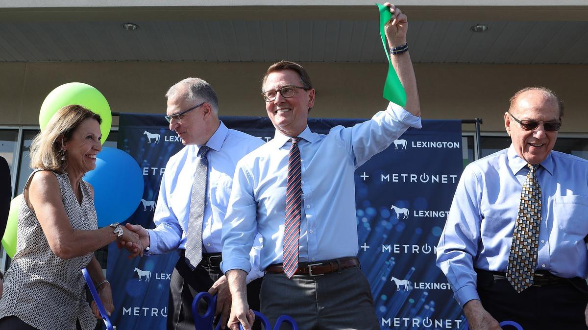 Mayor Jim Gray hoisted a piece of the ribbon Tuesday at MetroNet’s new retail location on W. Tiverton Way. Photo by Matt Goins