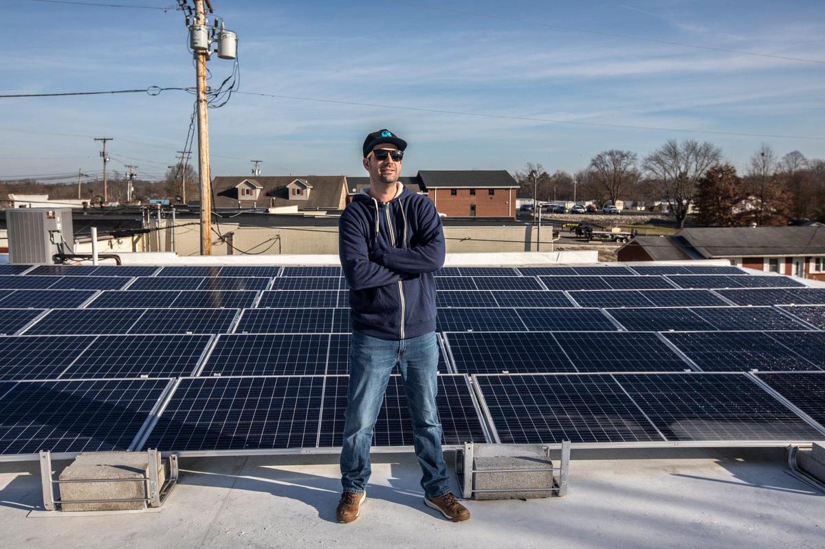 Kyle Robinson, owner of Print My Threads in Flatwoods, Ky., stands for a portrait in front of solar panels on the roof of the business Friday, Dec. 20, 2019.