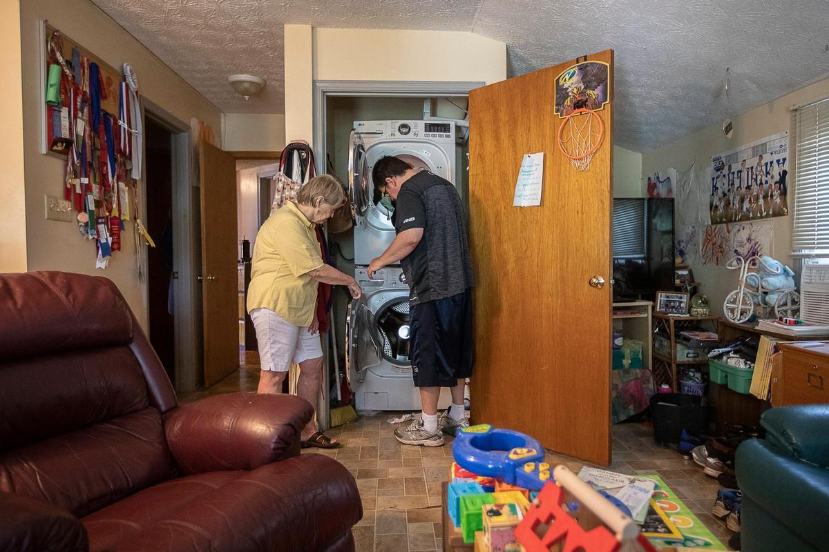 Marie Allison looks on as her son, Chris Riddell, moves laundry from the washing machine to the dryer in his accessory dwelling unit on the back of her home in Lexington, Ky., Friday, Aug. 9, 2019.