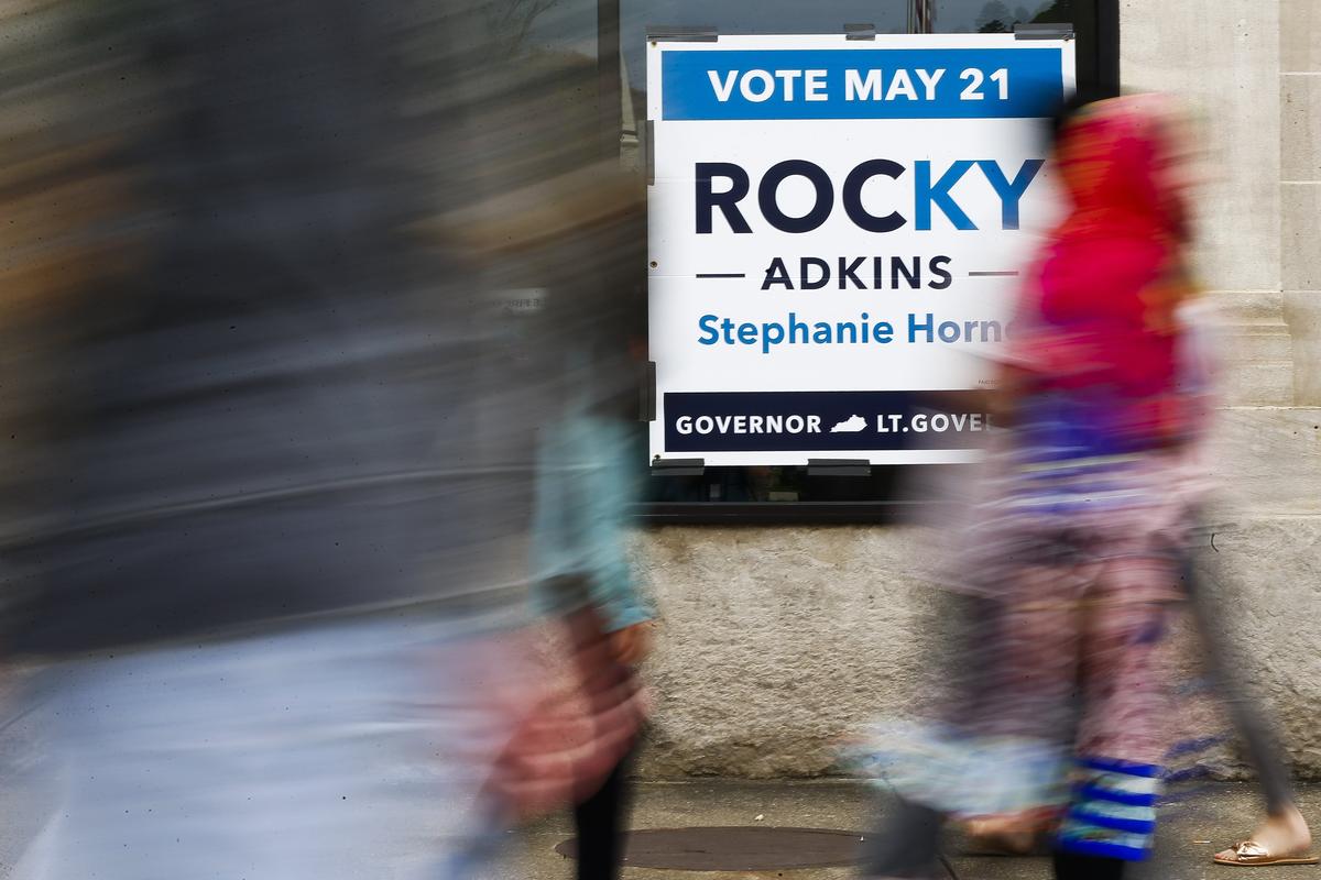 People walked past a Rocky Adkins campaign sign during Hillbilly Days Saturday in downtown Pikeville.