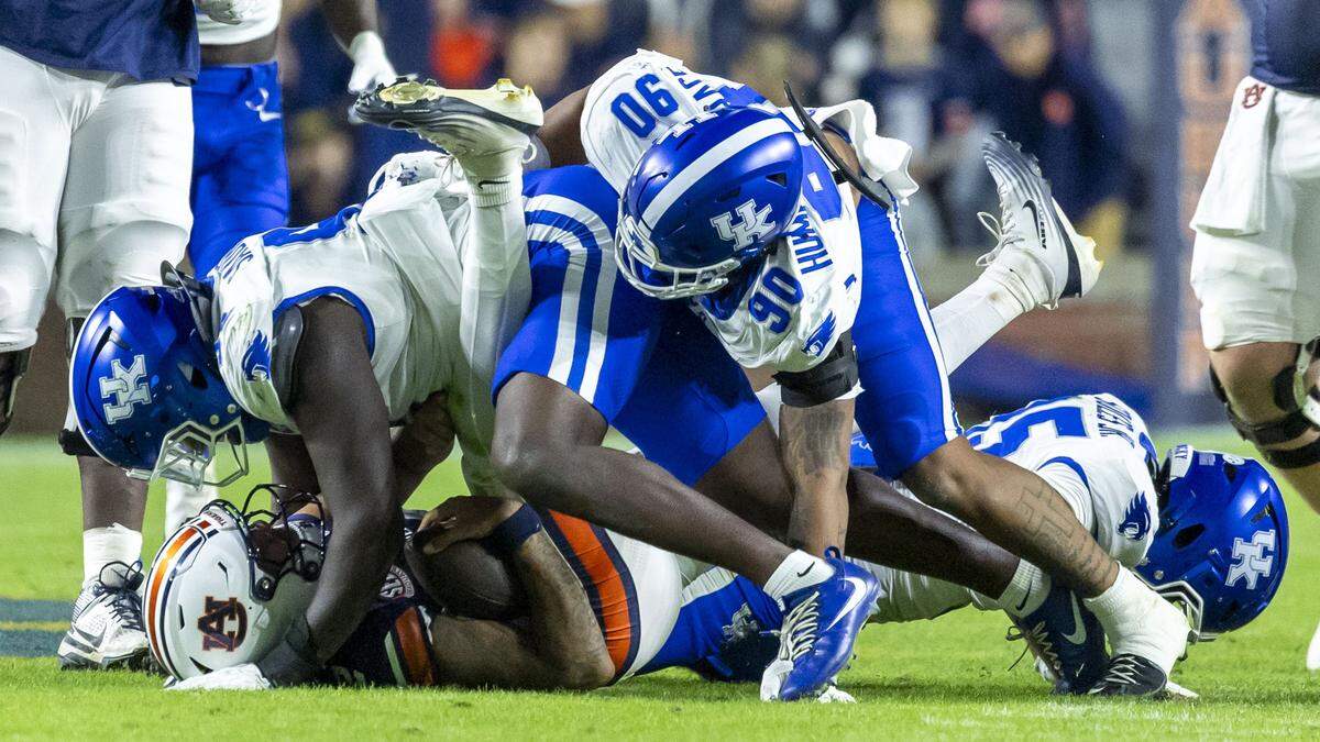 Kentucky defensive lineman Kahlil Saunders, left, defensive lineman Mi'Quise Humphrey-Grace (90) and linebacker Steven Soles Jr. (35) sack Auburn quarterback Ashton Daniels.