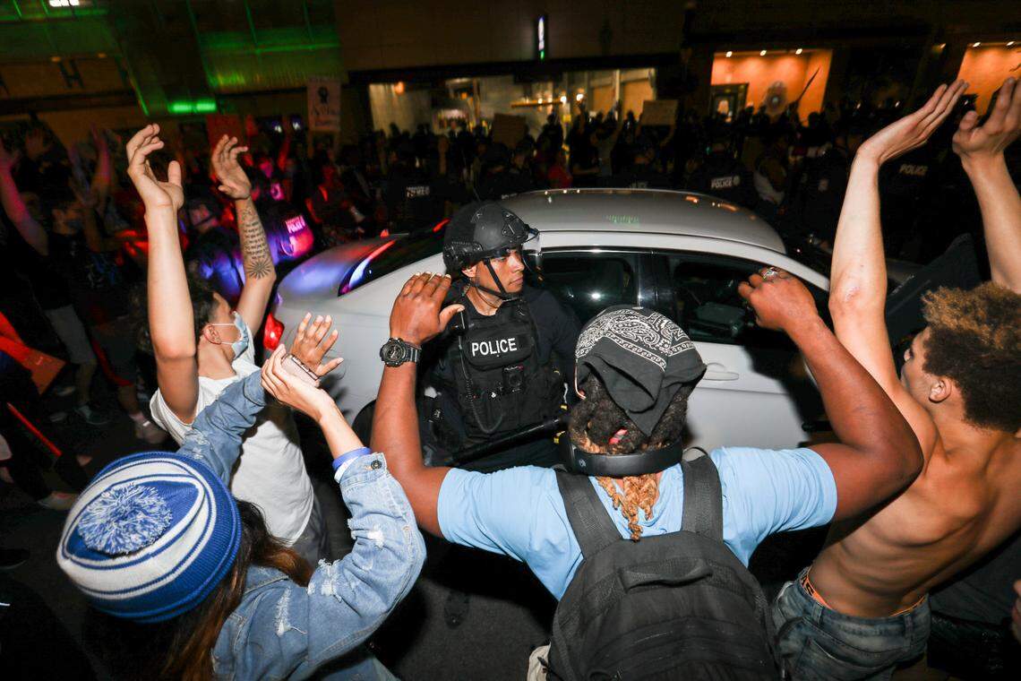 Demonstrators surround an unmarked police car in front of the police station while officers moved around the car to clear a path in Lexington, Ky., Wednesday, June 3, 2020.
