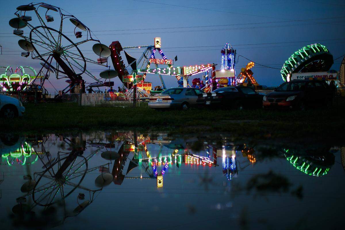 The midway at the Garrard County Fair is reflected in a puddle in Lancaster Tuesday, June 25, 2019.