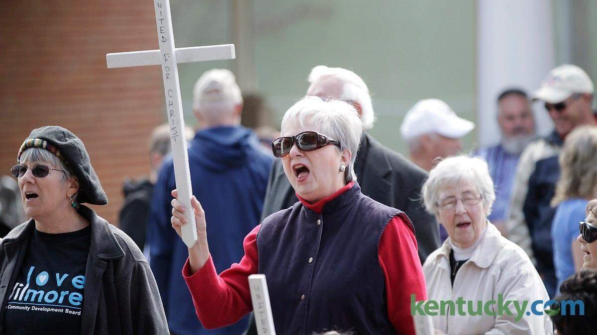 Wendy Stivers held her cross up high as she sang along  during a rally to keep the cross atop the water tower in downtown Wilmore, Ky., on Oct. 17, 2015.  Photo by Pablo Alcala | Staff
