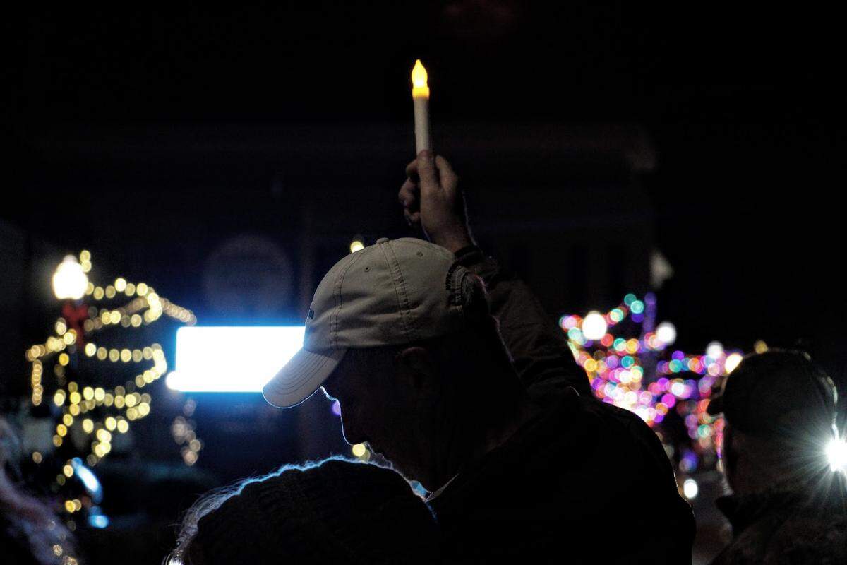 A man holds a battery-operated candle aloft during a Dec. 23, 2025, vigil in downtown London, Ky., a year after Douglas “Doug” Harless was gunned down by police in his home during a botched raid. Family and friends are still demanding accountability for his death a year later.