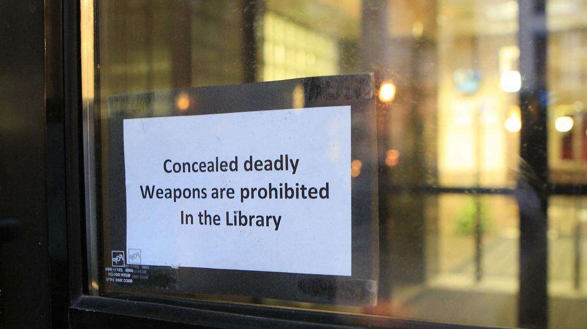 Signs on the Lexington Central Library doors prohibiting concealed deadly weapons were being taken down. Photo by Charles Bertram | Staff





