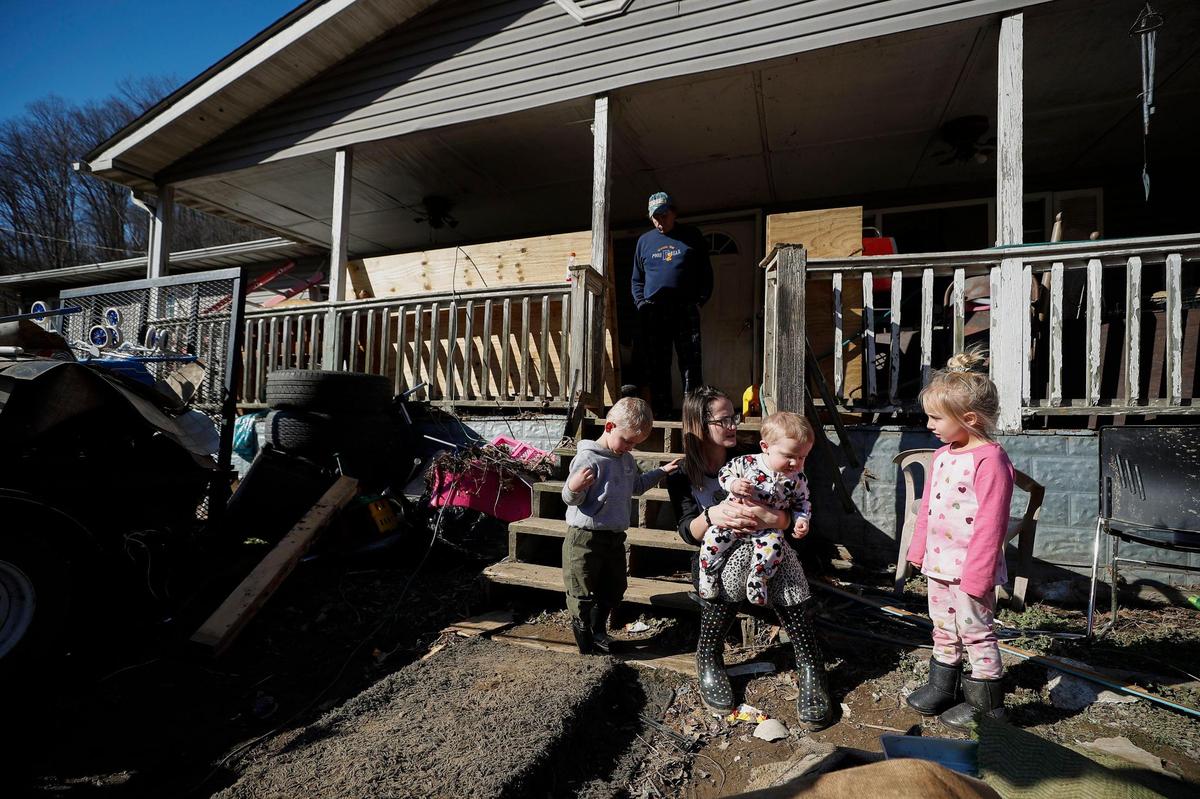 Raven Smith, holds her eight-month-old son Lenny Jude, as she sits with other family members, Liam Smith, 2, right, Keonna Jude, 4, and Michael Smith, all of Sidney on the porch of their trailer in Sidney, Ky., Thursday, Jan. 13, 2022. All of them were home on Jan. 1. as Big Creek rose nearly 30 feet and flooded the trailer.
