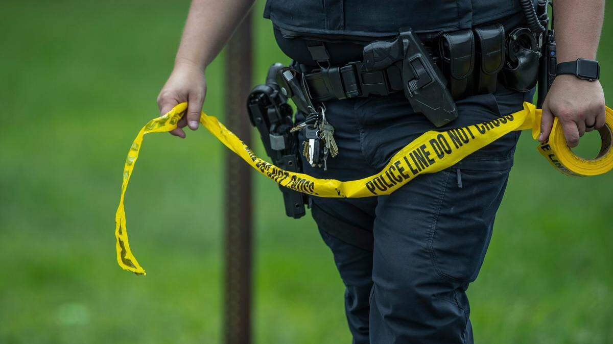 A Murray State University police office places police tape near the intersection of Poplar Street and Brentwood Avenue in Murray, Ky., on Saturday, Sept. 10, 2022. According to the Kentucky State Police, a man threw a Molotov cocktail style explosive in the direction of a group of female Murray State University students earlier in the day.
