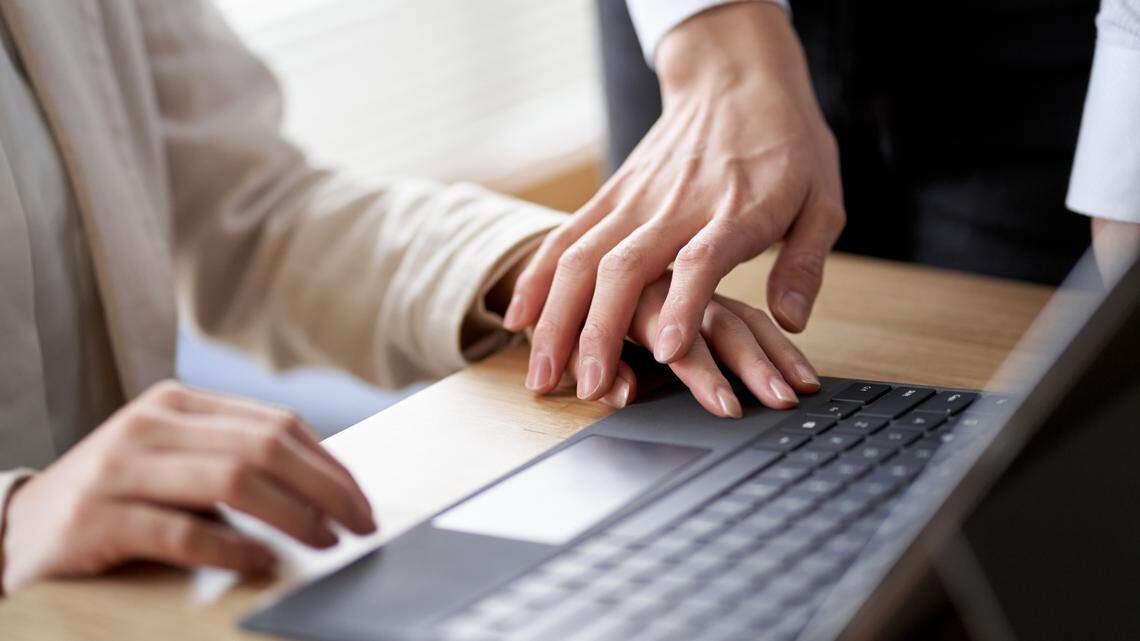 The stock photo shows a man's hand grabbing a woman's hand as she works at her computer.