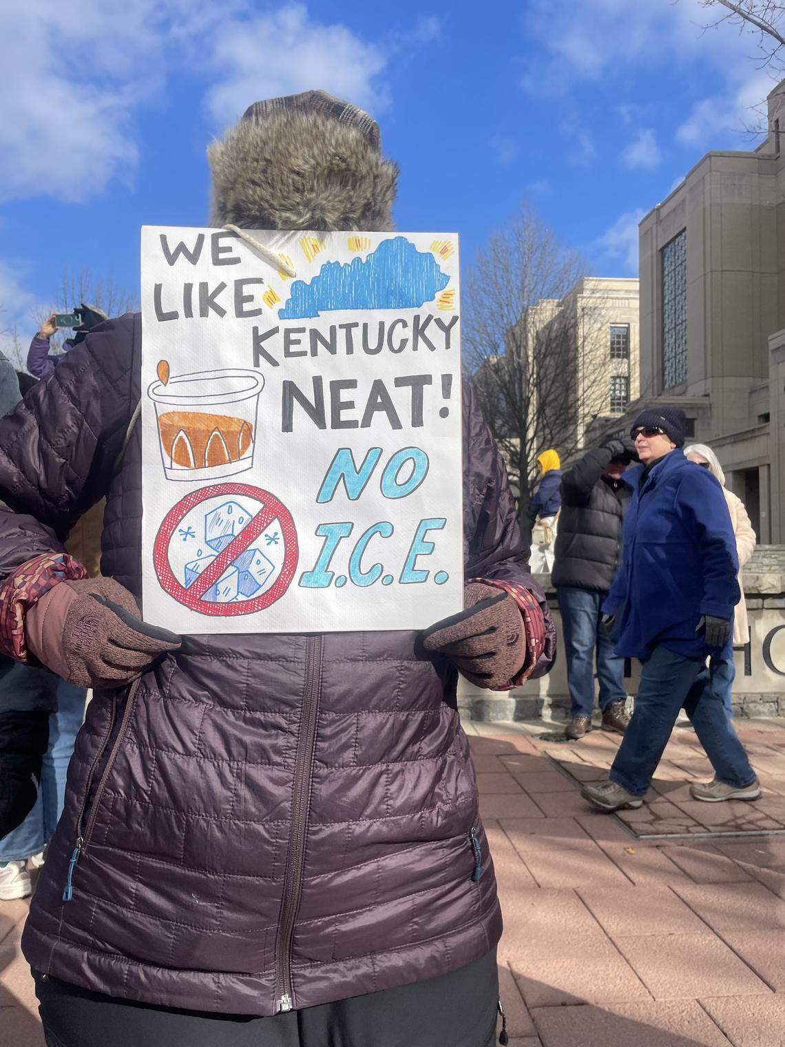 A woman holds a sign that says, “We like Kentucky, NEAT! NO ICE” at a protest Jan. 11, 2026, at courthouse square in downtown Lexington.