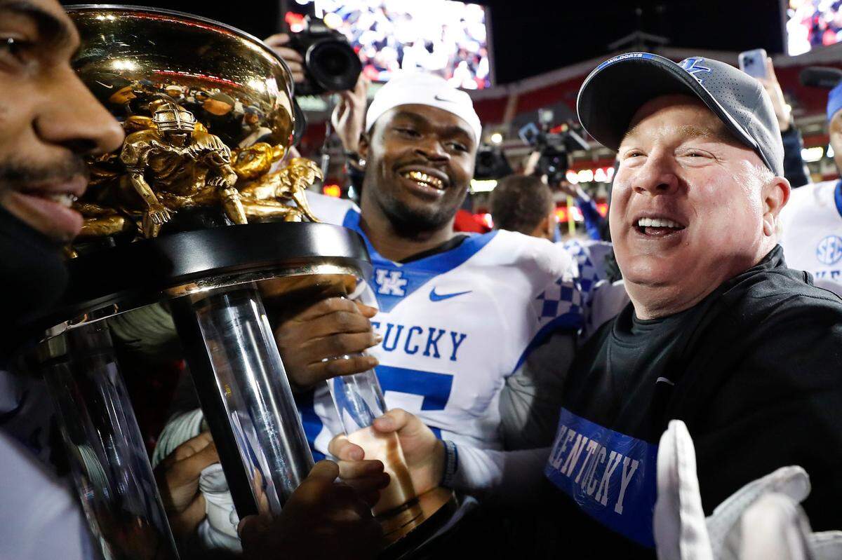 Kentucky head coach Mark Stoops celebrates with his team and the Governor’s Cup trophy after the Cats defeated Louisville 52-21 at Cardinal Stadium in Louisville on Nov. 27, 2021. Stoops, who is 4-4 against the Cardinals, lost the first three matchups of the series before winning the last three.