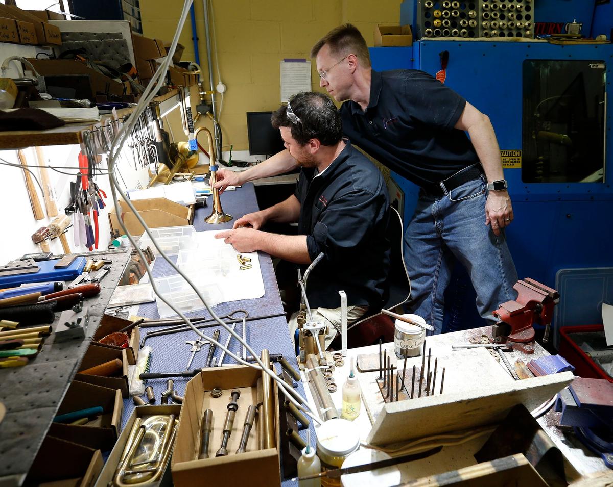 Peter Pickett, right, handed a trumpet bell to Robert Lawson as he assembled a trumpet at Pickett Brass and Blackburn Trumpets, 308 North Ashland Avenue in Lexington. Peter Pickett is a musician who used to be an engineer.