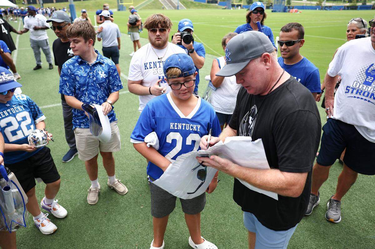 Kentucky head coach Mark Stoops signs memorabilia for fans after the team’s annual Fan Day open practice at the Joe Craft Football Training Center practice fields in Lexington on Saturday.