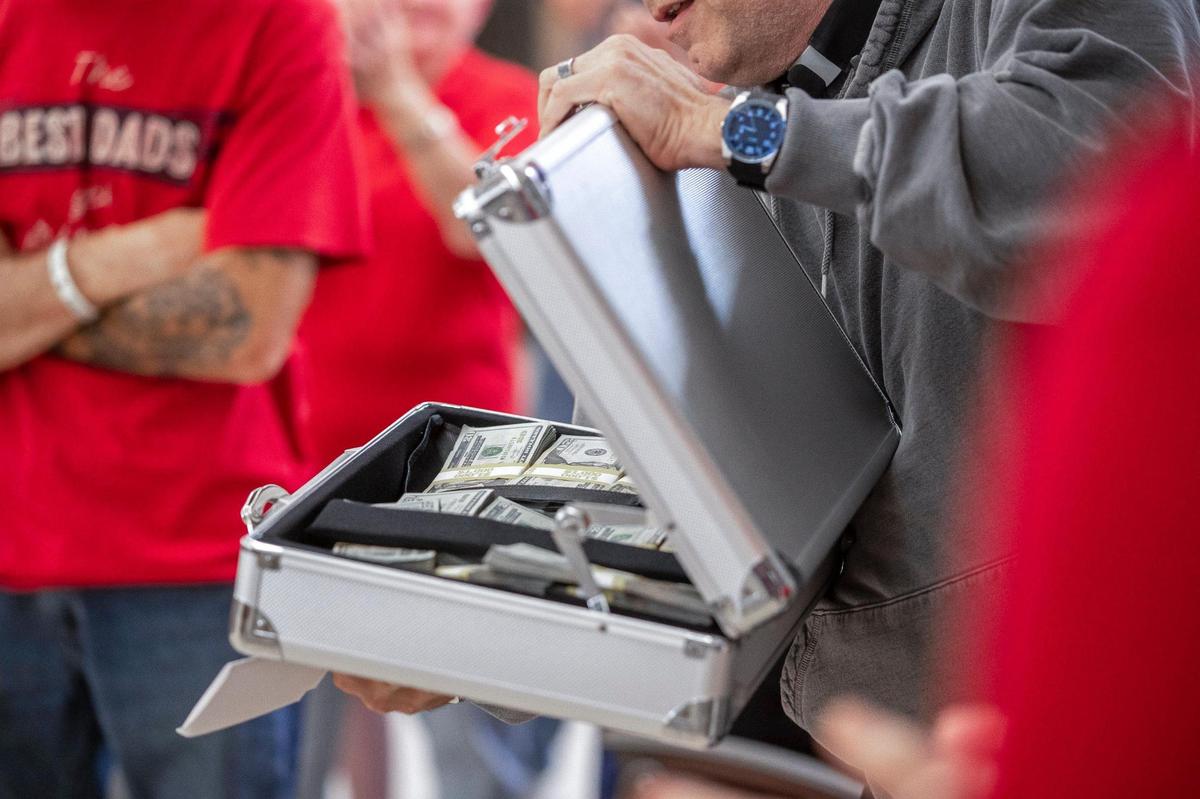 Father Jim Sichko — the Papal Missionary of Mercy from Lexington — opens a case containing $75,000 that he gave Gwen and Arthur Christon to help reopen the Isom IGA grocery store they own.