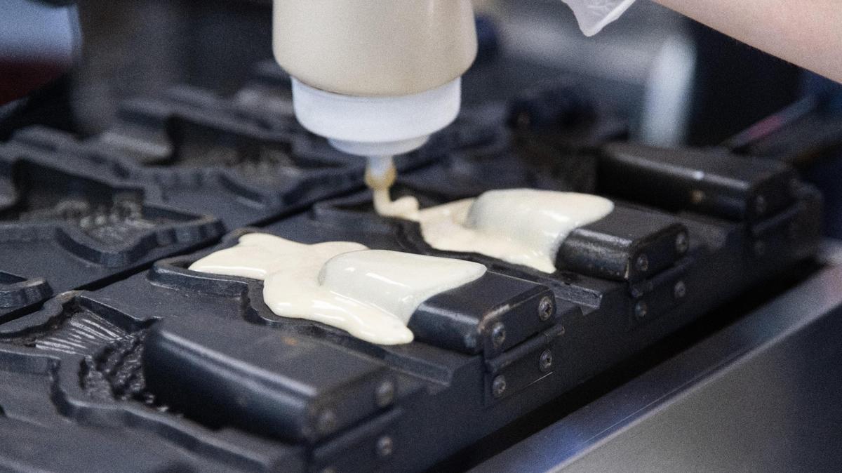 Waffle batter is poured into hot molds to make taiyaki fish cones, but don’t worry, they don’t actually taste like taiyaki fish.