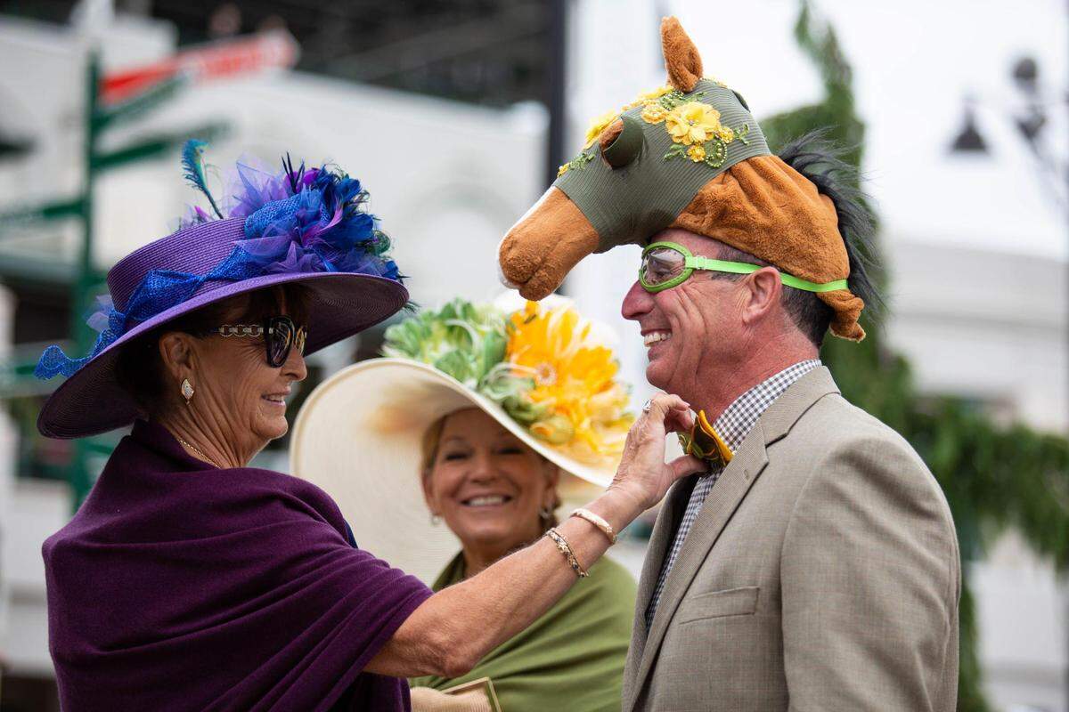 Janie Westcott of San Ramon, Calif., left, straightens Joe Conforto’s bow tie while his wife Michele, middle, smiles near the paddock at Churchill Downs in Louisville, Ky., on Saturday, May 7, 2022. Of the people who wore hats, you either went fancy or comical.