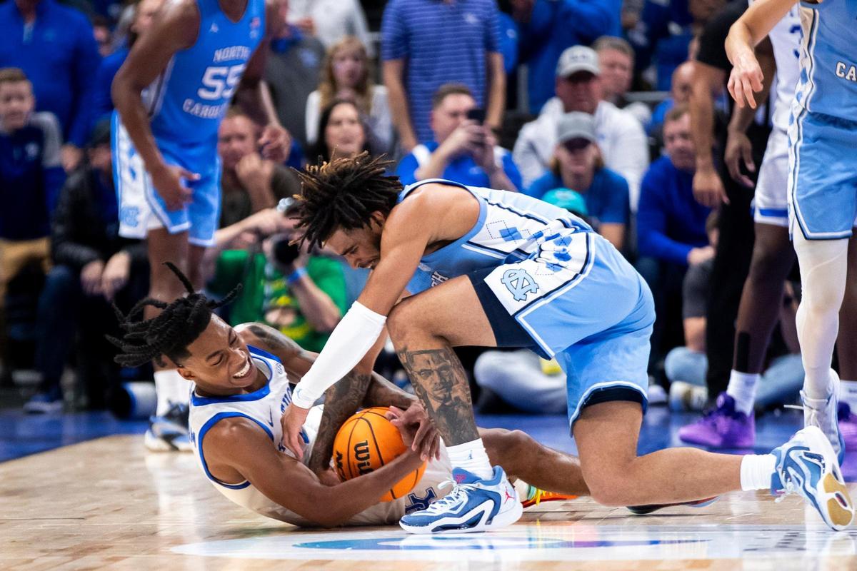 Kentucky freshman guard Rob Dillingham, left, dives for a loose ball against North Carolina guard RJ Davis during the CBS Sports Classic. Dillingham is averaging more than four rebounds per game.