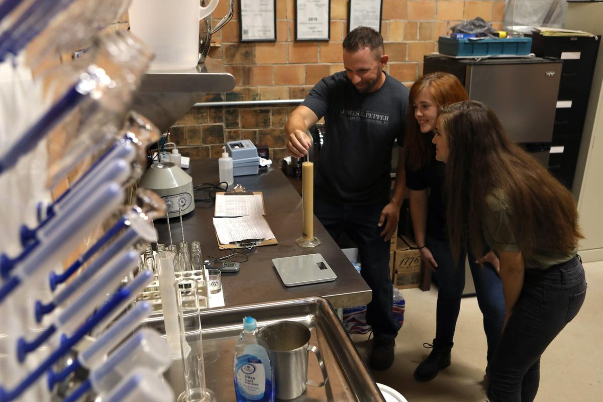 Jenna Dowell and Alex Keeling, both interns from UK's distilling program, look on as master distiller Aaron Schorsch checked sugar levels in the mash in the lab at James E. Pepper Distillery on Manchester Street.
